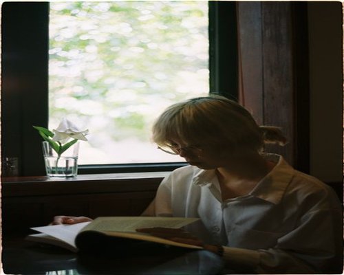 person reading a book near a window